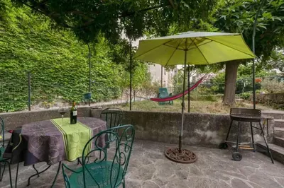 a patio with a table and a green umbrella at Gîte vigneron in Félines-Minervois