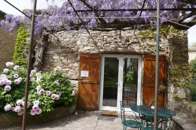 a table and chairs in front of a building with purple flowers at Gîte vigneron in Félines-Minervois