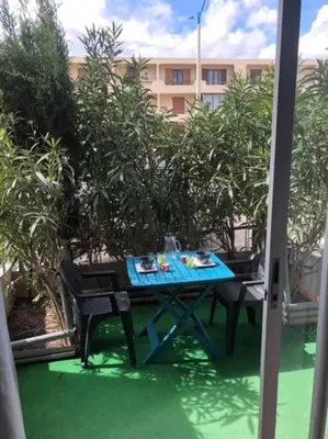 a blue table and chairs on a patio with trees at Appartement rénové RDC terrasse 200m plage in Port-la-Nouvelle