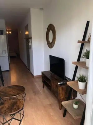 a living room with a tv and a table and chairs at Appartement rénové RDC terrasse 200m plage in Port-la-Nouvelle