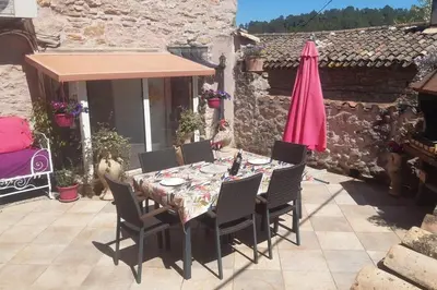 a table with chairs and a pink umbrella on a patio at LA PASTOURELLE in Saint-Chinian