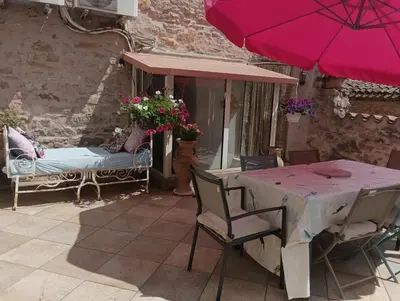 a patio with a table and a pink umbrella at LA PASTOURELLE in Saint-Chinian
