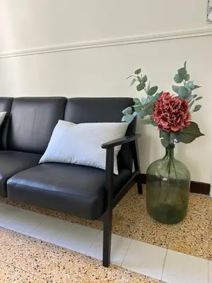 a black couch and a vase with a flower in it at Maison Paulette - charme et authenticité in Bizanet