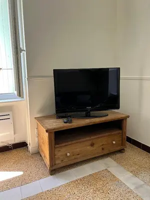 a flat screen tv sitting on top of a wooden entertainment center at Maison Paulette - charme et authenticité in Bizanet