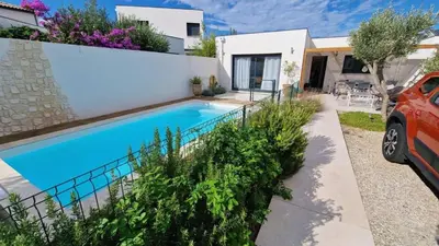 a villa with a swimming pool in front of a house at L’Oliveraie in Narbonne