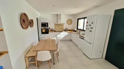 a kitchen with a wooden table and a white refrigerator at L’Oliveraie in Narbonne