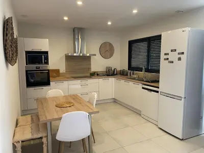 a kitchen with a table and a white refrigerator at L’Oliveraie in Narbonne
