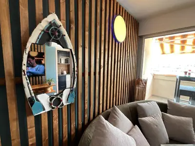 a mirror on a striped wall with a couch at Confort sur le port in Gruissan
