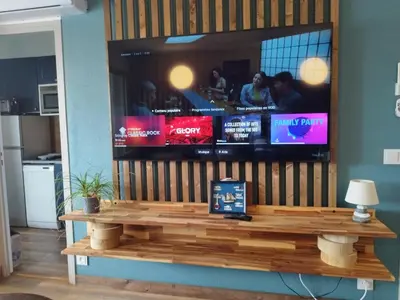 a large television on a wall with a table at Confort sur le port in Gruissan