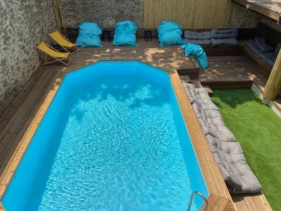 a swimming pool in a house with blue water and chairs at T4 bord canal du midi, piscine in Homps