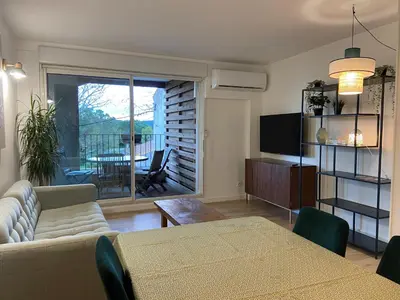 a living room with a couch and a table and a television at T2 bord du canal du midi piscine in Homps