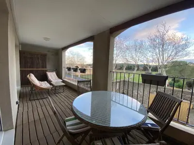 a patio with a glass table and chairs on a deck at T2 bord du canal du midi piscine in Homps