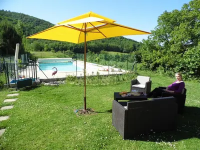 a woman sitting in a chair under a yellow umbrella at Domaine du Bourdil au pays Cathare in Chalabre