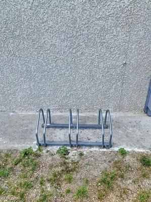 a metal bench sitting on the side of a sidewalk at Les pénates du pastel - Jardin & Terrasse in Villefranche-de-Lauragais