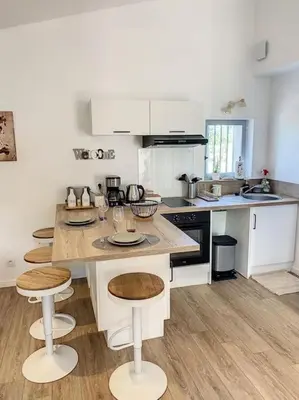 a kitchen with a large island with stools in it at Les pénates du pastel - Jardin & Terrasse in Villefranche-de-Lauragais