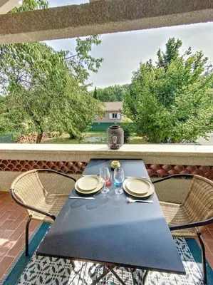 a black table with two glasses and two chairs on a patio at Les pénates du pastel - Jardin & Terrasse in Villefranche-de-Lauragais