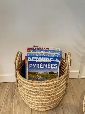a basket filled with books sitting on a floor at Les pénates du pastel - Jardin & Terrasse in Villefranche-de-Lauragais