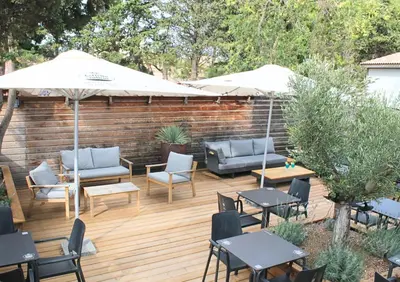 a patio with chairs and tables and an umbrella at Domaine de la Palme in Lapalme