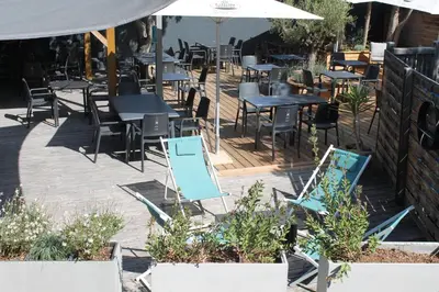an outdoor patio with tables and chairs and umbrellas at Domaine de la Palme in Lapalme