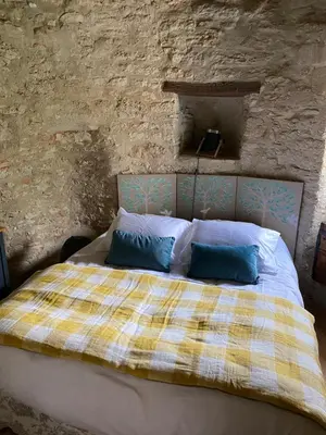 a bedroom with a bed in a stone wall at Souplassens in Rieumajou