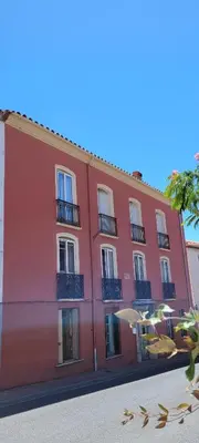 a red building with windows and umbrellas on a street at Comme à la Maison - Accueil tout Public - Groupes - Rando - Vélos - Motos in Saint-Paul-de-Fenouillet