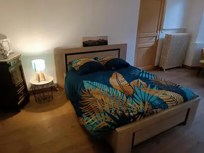 a bedroom with a bed with a blue comforter and a lamp at L'écrin in Lacroisille