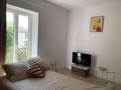 a white room with a bed and a television at Appartement cœur de village Numéro1 in Peyriac-de-Mer