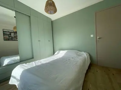 a bedroom with a white bed and a mirror at Appartement 2 chambres +parking in Narbonne
