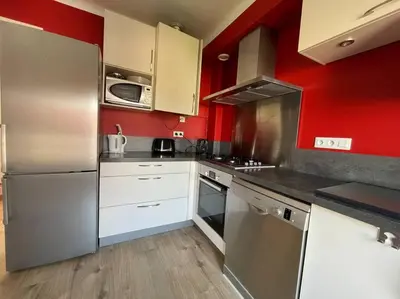 a kitchen with red walls and stainless steel appliances at Appartement 2 chambres +parking in Narbonne