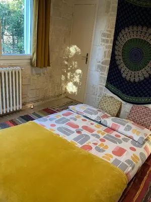 a bedroom with a bed with a colorful blanket at Gîte avec jacuzzi, et accès privé à la rivière in Ladern-sur-Lauquet