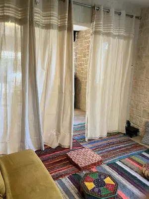 a living room with white curtains and a rug at Gîte avec jacuzzi, et accès privé à la rivière in Ladern-sur-Lauquet