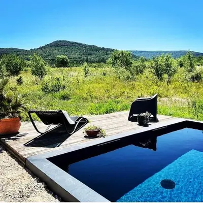 a swimming pool with two chairs and a wooden deck at Piano apartment in Taurize