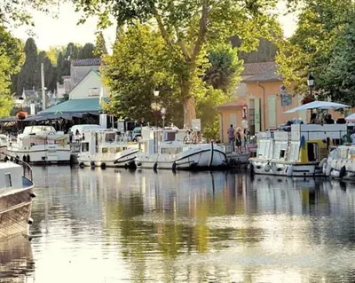 a group of boats are docked in a river at Loccitan in Capestang