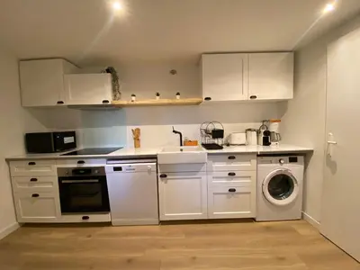 a kitchen with white cabinets and a washing machine at T3 bis bord du canal du midi piscine in Homps