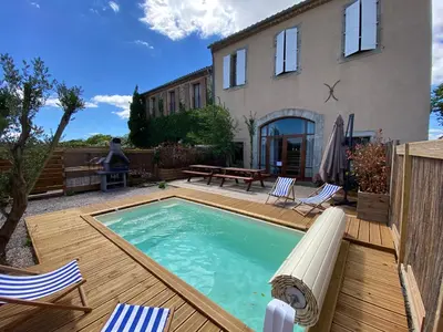 a backyard with a pool and chairs and a house at Maison, canal du midi piscine in Homps