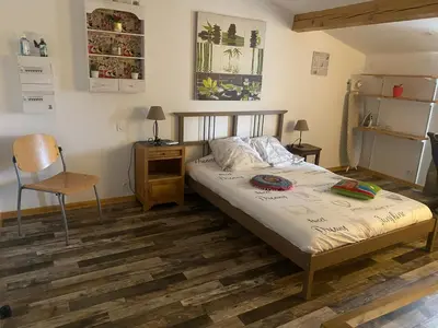 a bedroom with a bed with a chair and a table at La P’tite Maison de David in Saint-Hilaire