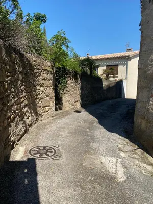 an alley with a stone wall and a manholephalt at La P’tite Maison de David in Saint-Hilaire