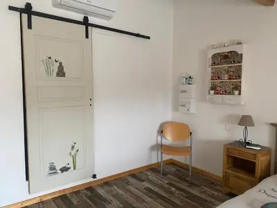 a sliding door in a bedroom with a bed and a chair at La P’tite Maison de David in Saint-Hilaire