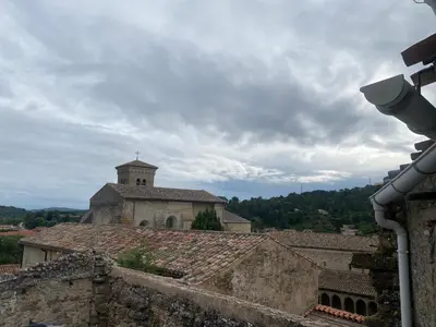 an old building with a church in the background at La P’tite Maison de David in Saint-Hilaire
