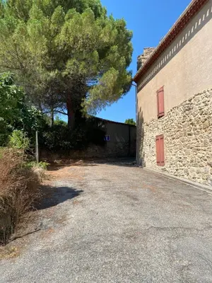 a driveway next to a stone building with a tree at La P’tite Maison de David in Saint-Hilaire