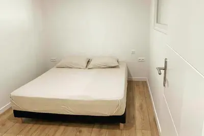 a bed in a room with white walls and wooden floors at Cozy & Elegant Appartement Narbonne in Narbonne