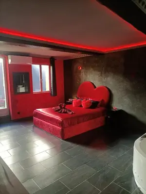 a bedroom with a red bed with a heart shaped headboard at L'instant romance Le Romantique in Castelnaudary