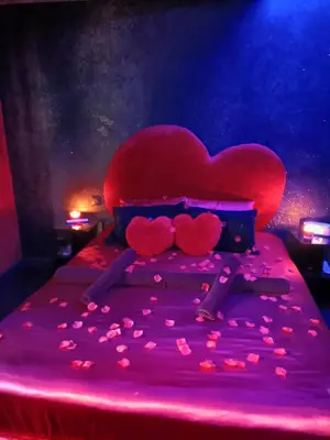 a bed with a heart shaped headboard with pink lighting at L'instant romance Le Romantique in Castelnaudary