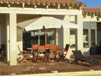 a patio with a table and chairs and an umbrella at Serene Villa Stay near Narbonne in Narbonne