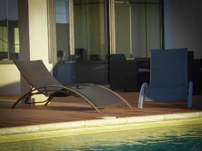 two chairs sitting next to a pool in a building at Serene Villa Stay near Narbonne in Narbonne