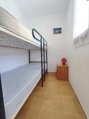 a bedroom with a bunk bed and a table at APPARTEMENT DE VACANCES A LA MER DANS RESIDENCE SECURISEE in Gruissan