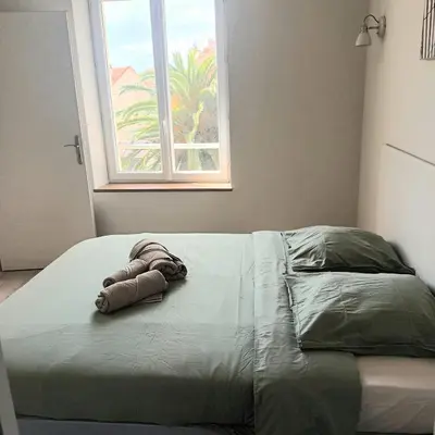 a bed with a towel on it with a window at Le Baya - Appt proche des Halles in Narbonne