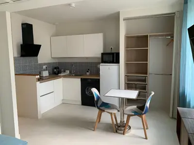a kitchen with white cabinets and a table and chairs at Le Woltu - Appt proche des Halles in Narbonne
