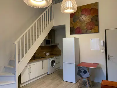 a kitchen with a white refrigerator and a staircase at Le Woltu - Appt proche des Halles in Narbonne