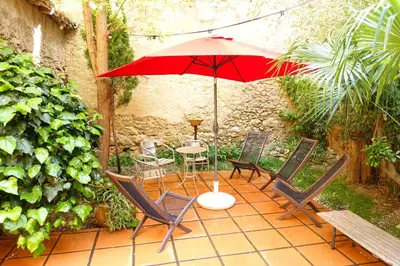 a patio with a table and chairs and an umbrella at GîTE-FAMILLE NOMBREUSE-SÉMINAIRE-PATIO in Ornaisons
